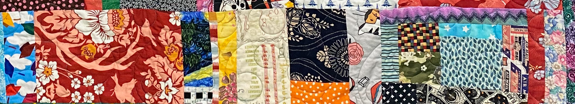 A portion of a scrap quilt, featuring a wide variety of printed designs on fabric